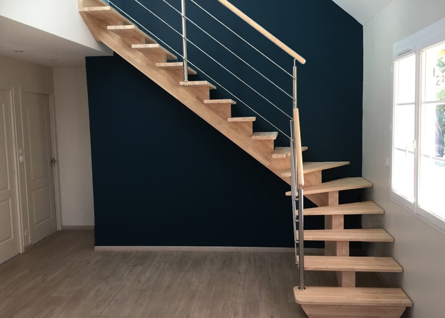 Escalier contemporain avec un mur d'accent bleu marine, marches en bois et balustrade en inox.