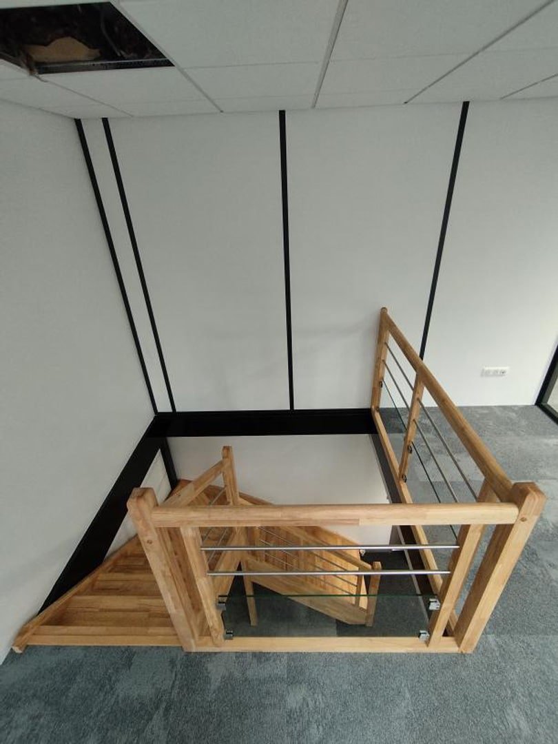Escalier en bois contemporain dans un espace de bureau, avec garde-corps en bois et métal noir.