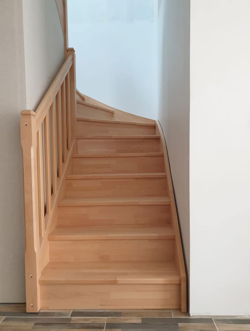 Escalier en bois robuste encadré par un garde-corps assorti dans une maison aux tons neutres.