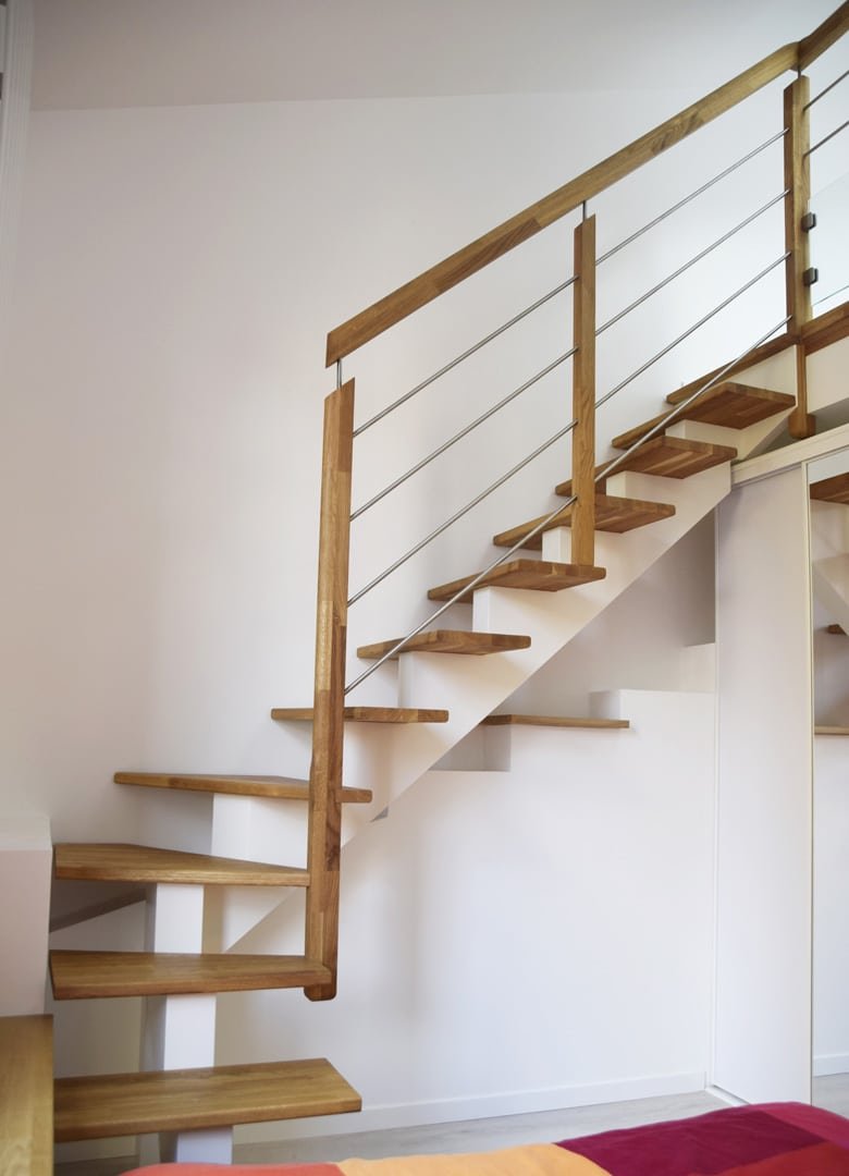 Escalier flottant moderne avec marches en bois clair et garde-corps à câbles dans un intérieur épuré