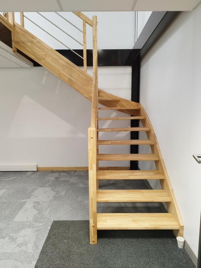 Vue latérale d'un escalier en bois avec des marches flottantes et garde-corps en bois et câbles.