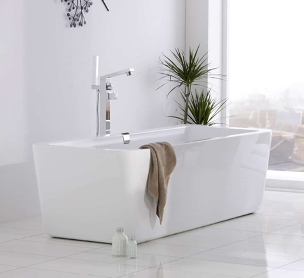 Baignoire rectangulaire blanche moderne dans une salle de bain lumineuse avec une grande fenêtre, des plantes vertes, et un robinet design chromé. Un serviette ma