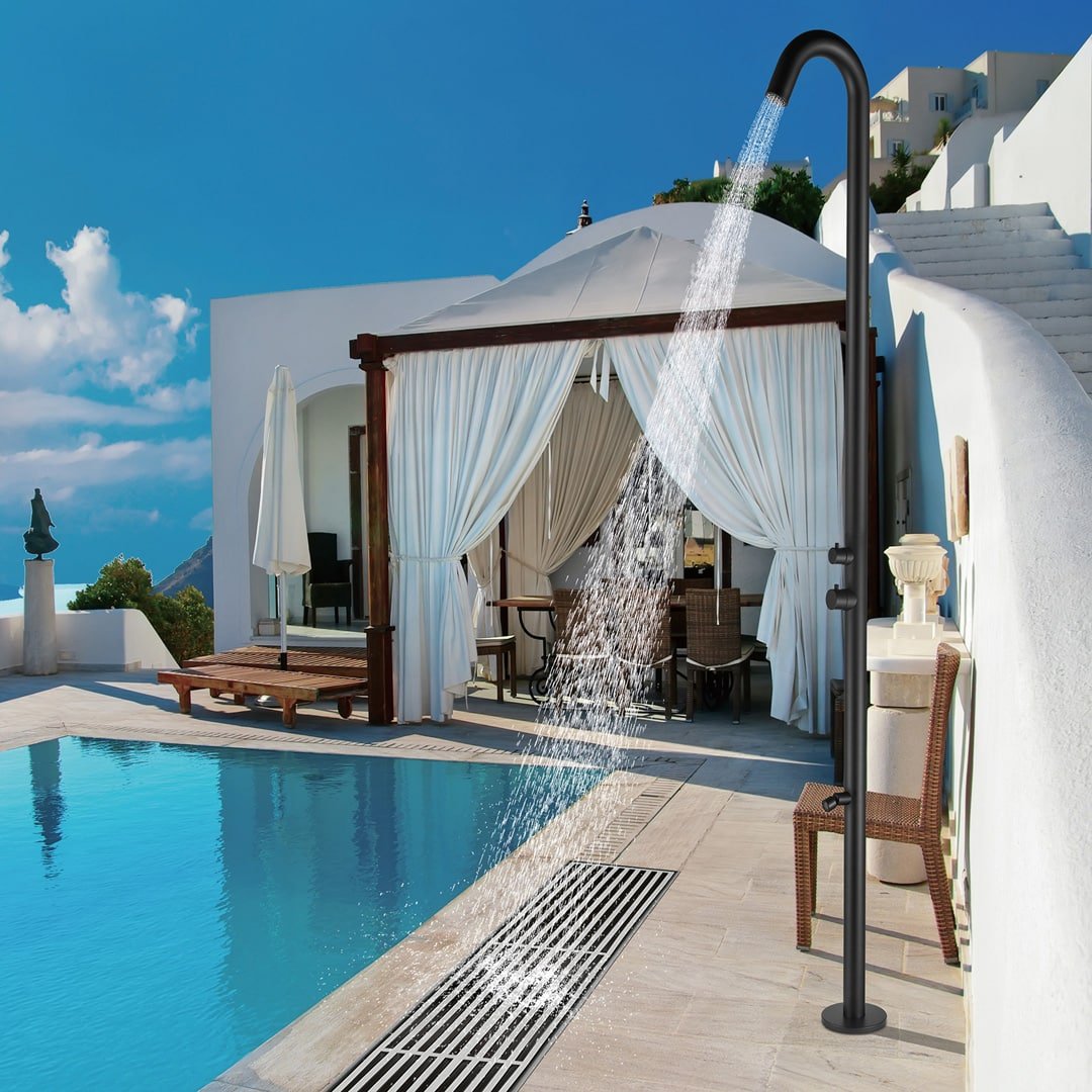 Douche extérieure élégante à côté d'une piscine avec des rideaux blancs flottants et un mobilier de terrasse en bois, dans un cadre de villa luxueuse.