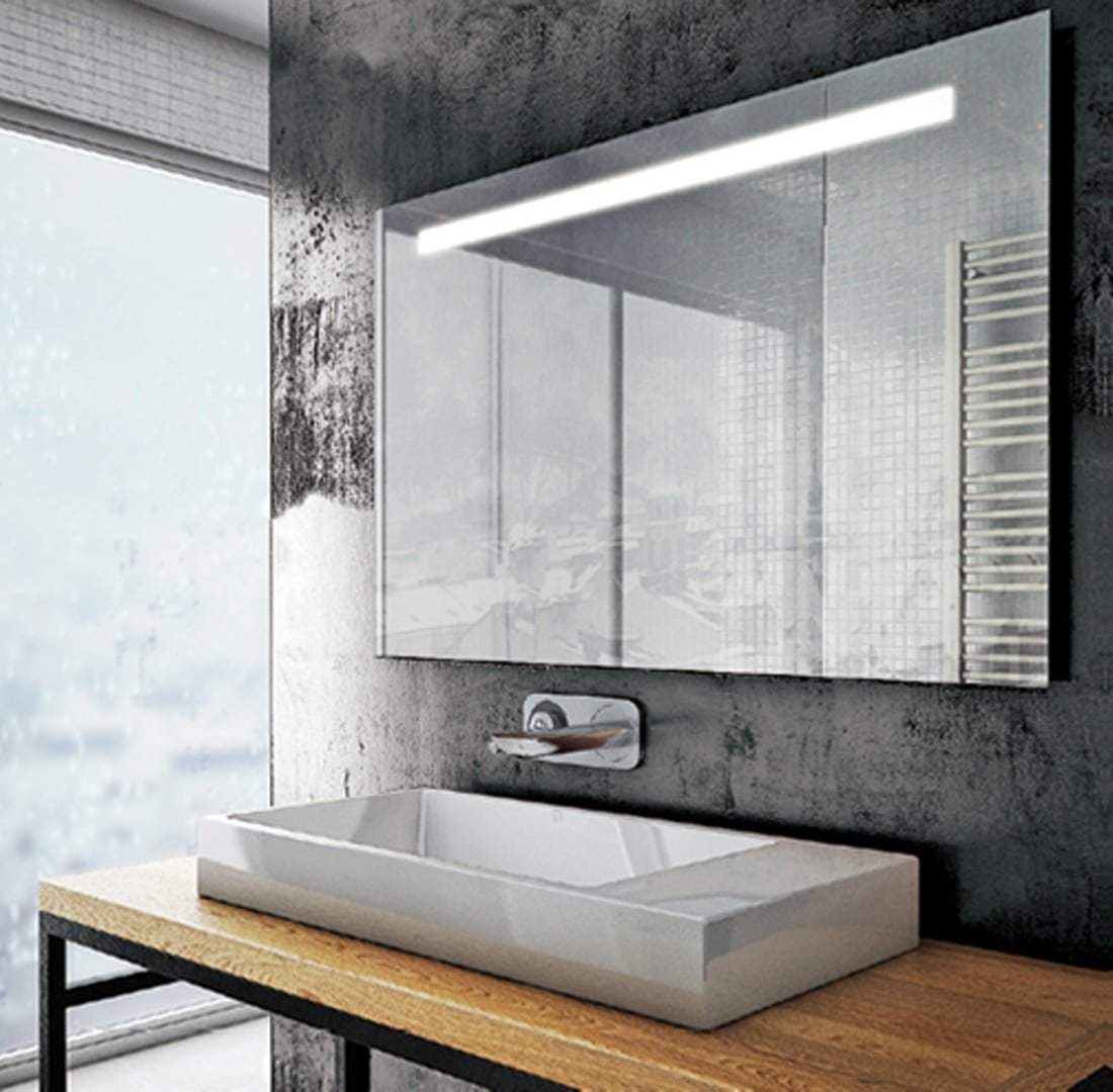 Salle de bain contemporaine avec un grand miroir rectangulaire doté d'un éclairage vif en partie supérieure, contre un mur texturé reflétant un paysage urbain.