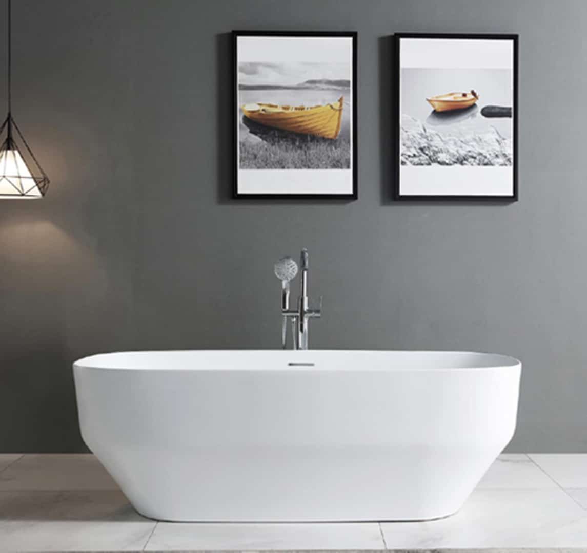 Salle de bain épurée avec une baignoire blanche autonome, un robinet sur pied, et deux cadres noirs affichant des images de bateaux sur le mur gris. Une suspensio